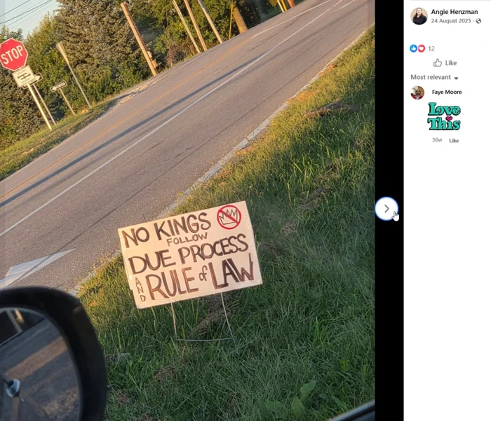 A roadside placard beside a paved two-lane street reads "NO KINGS FOLLOW DUE PROCESS AND RULE OF LAW."